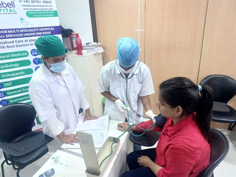 Bluebell staff in surgical caps attending to a visitor at a health camp desk
