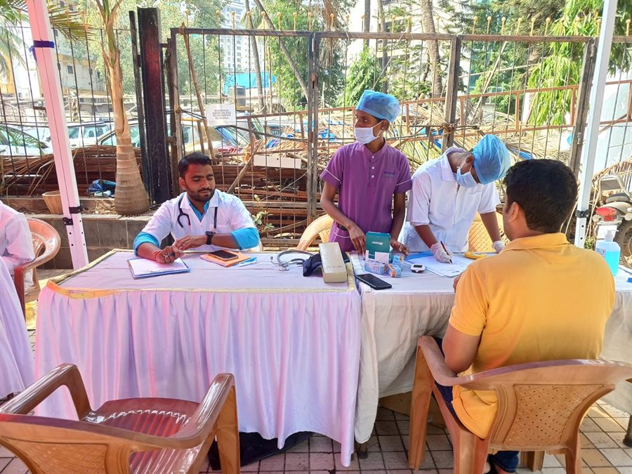 Staff consulting visitors under a gazebo at an outdoor camp