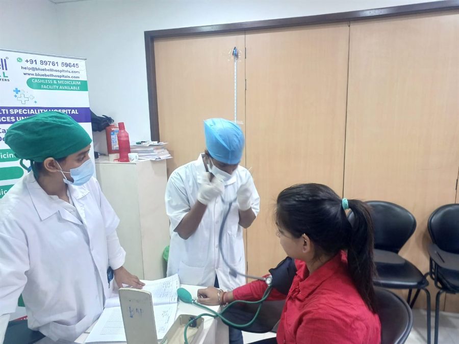 Two staff members in surgical caps consulting a visitor at a camp desk
