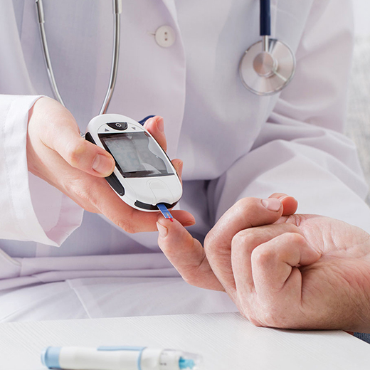 Clinician taking a blood glucose reading from a patient’s fingertip